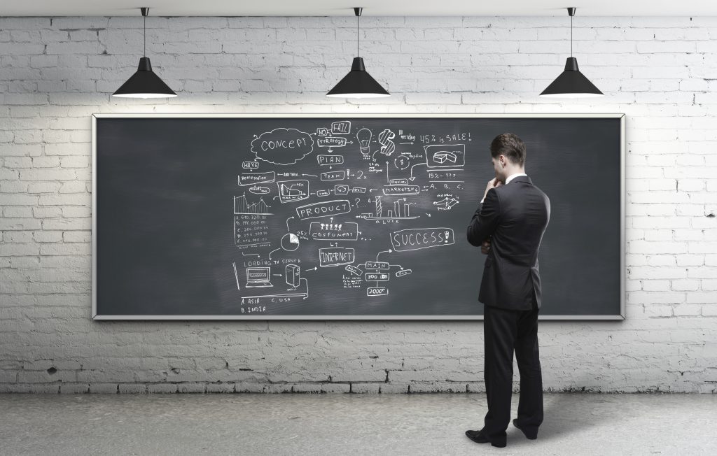 businessman looking at business strategy on blackboard