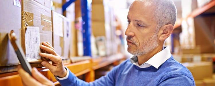 Warehouse manager checking a shipping label against a handheld device during ERP integration testing