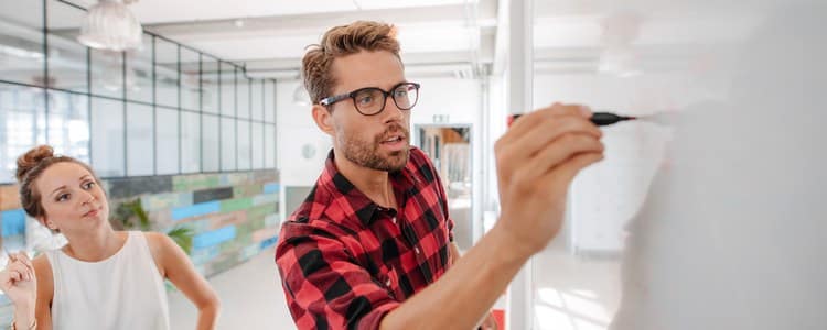 Two colleagues at a whiteboard mapping ERP system integration requirements