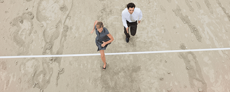 Two business professionals walking toward a white line drawn across the sand, representing how to address change readiness gaps before kickoff