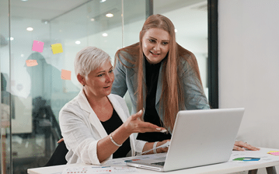 Two colleagues review digital transformation metrics on a laptop in a modern office